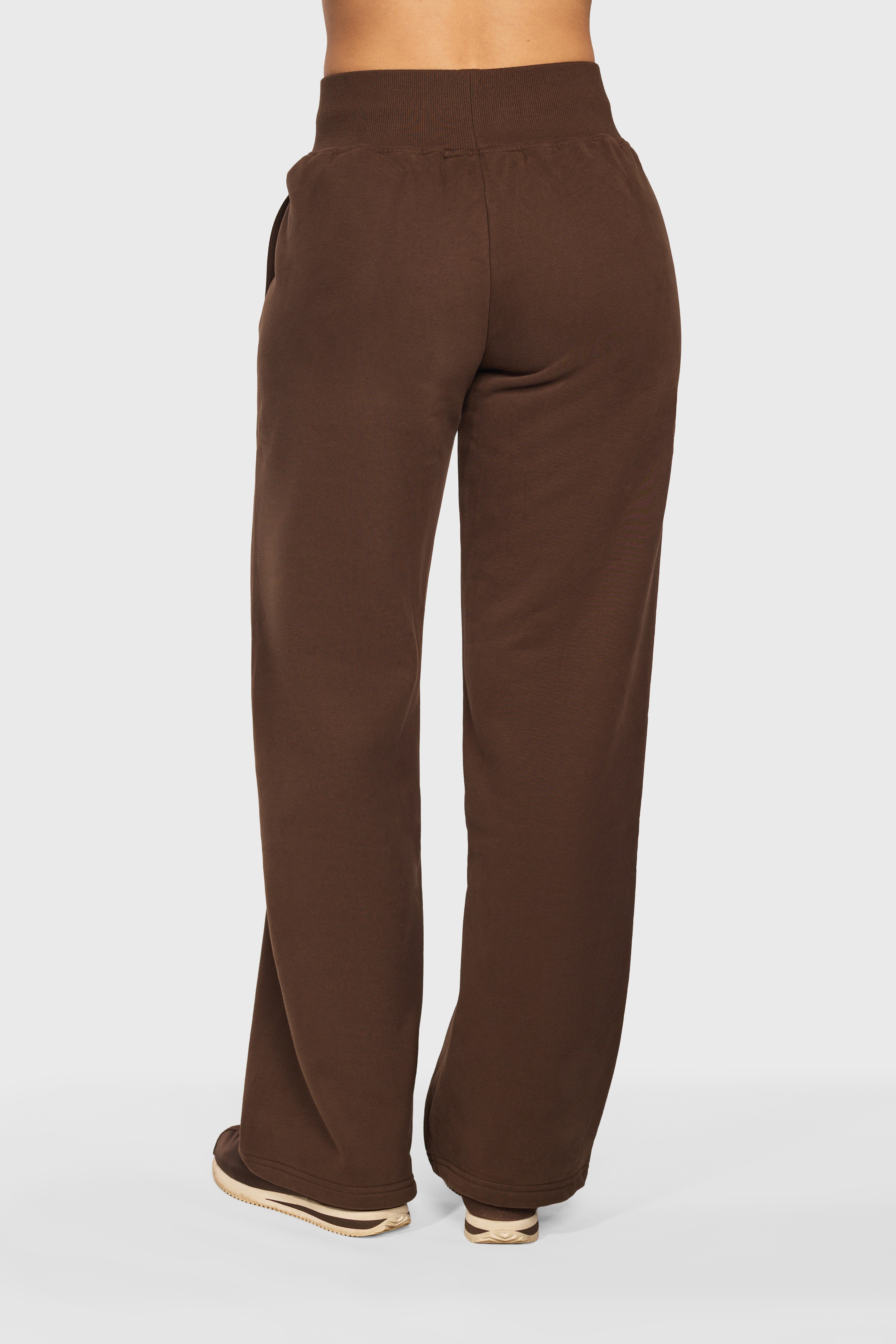 Model draagt de Soft Lounge Wide Leg Jogger van Gymforce in donkerbruin.